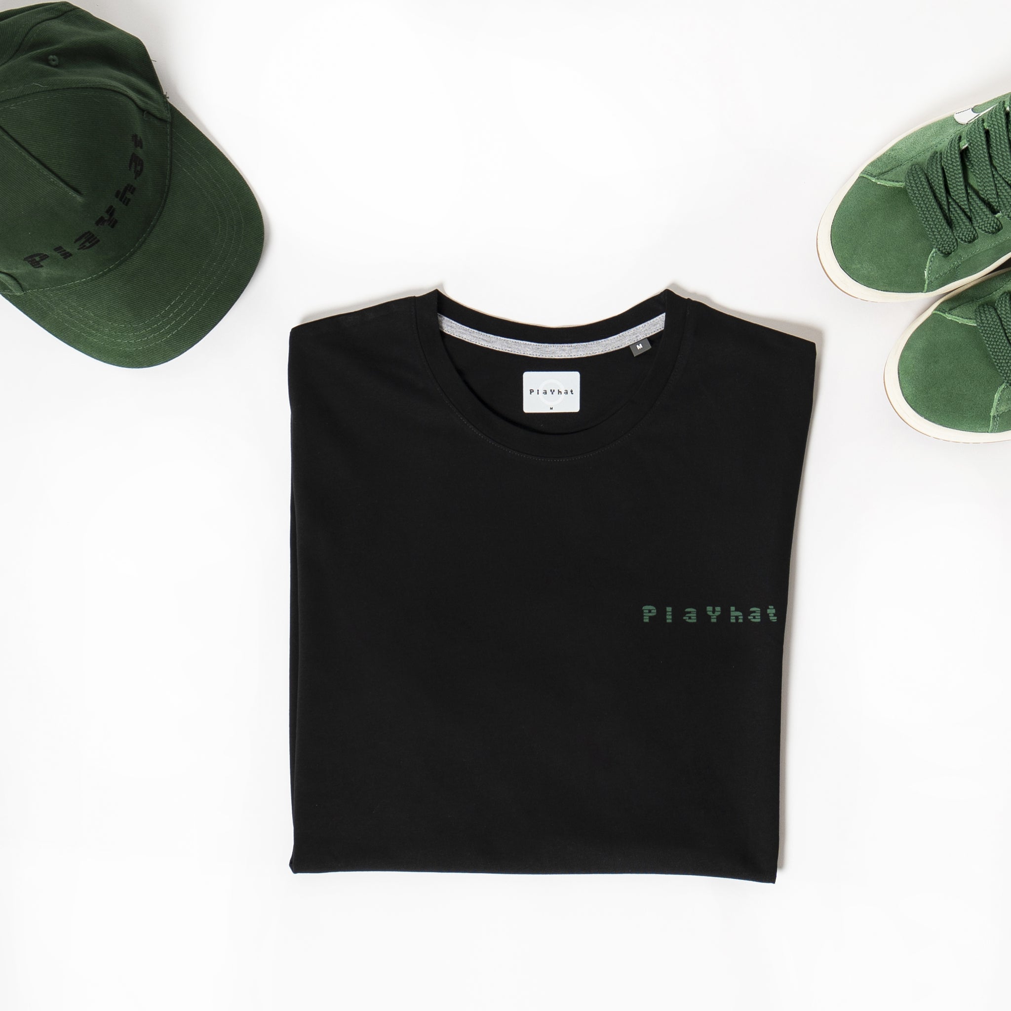 T-shirt nera con sneakers e cappello verde abbinati