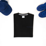 T-shirt nera con logo blu abbinata alle sneakers blu e al cappello